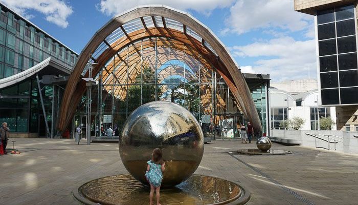 child playing in the water surrounding the steel balls in the Sheffield Peace Gardens