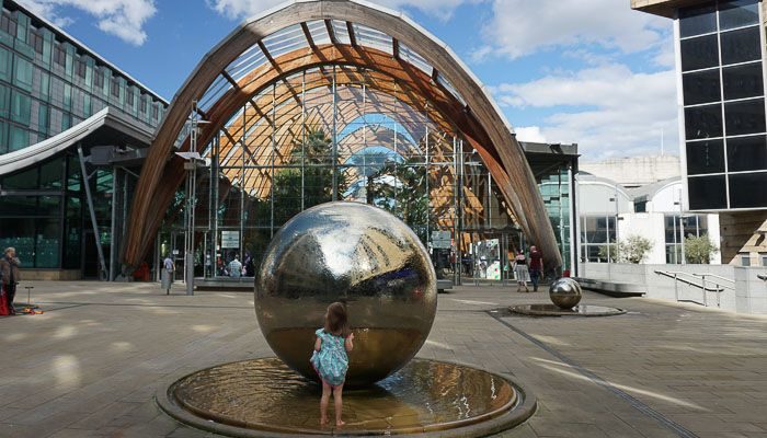child playing in the water surrounding the steel balls in the Sheffield Peace Gardens