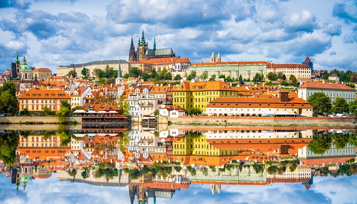 a city with red roofs and buildings reflected in water