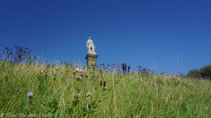 a statue on a pedestal in a grassy field