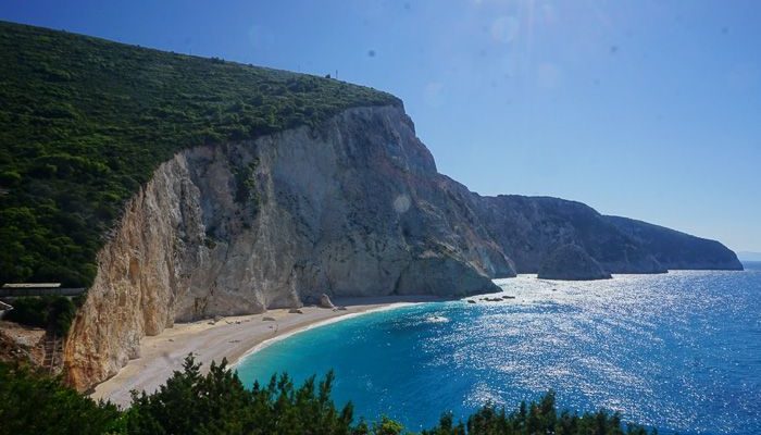a beach with a body of water and a cliff