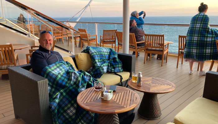 Jason snuggling under a blanket onboard Celebrity Eclipse at sunset