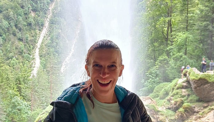 a woman smiling in front of a waterfall