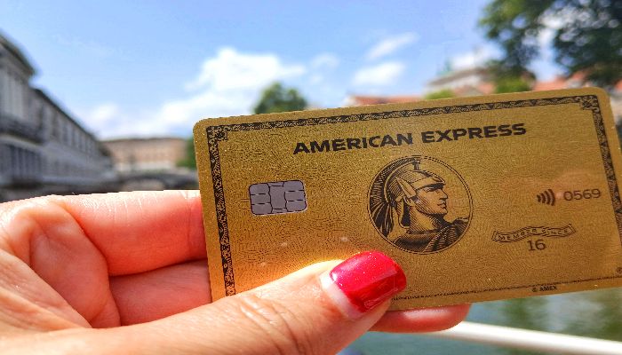 a hand holding a American Express Gold credit card