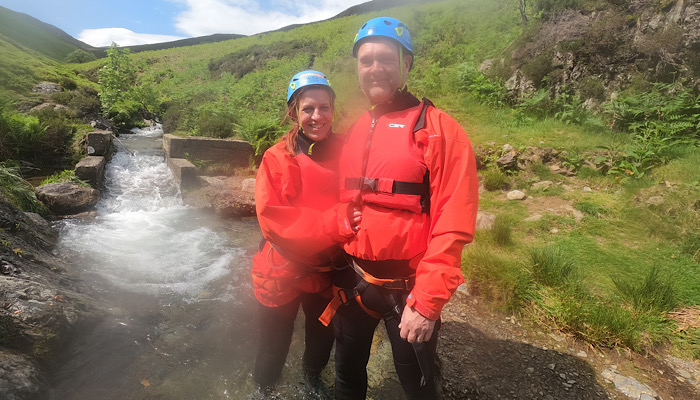 a man and woman wearing helmets and standing in water