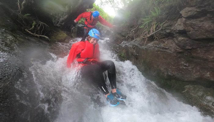 a couple of people wearing helmets and standing on a waterfall