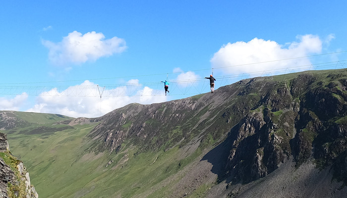 people walking on a rope over a mountain