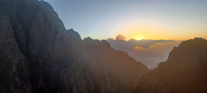 a mountain range with the sun setting behind it